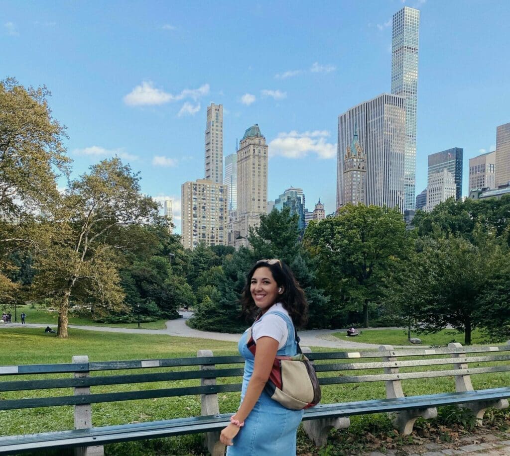 Berenice Santos in a big city park approaching a line of benches